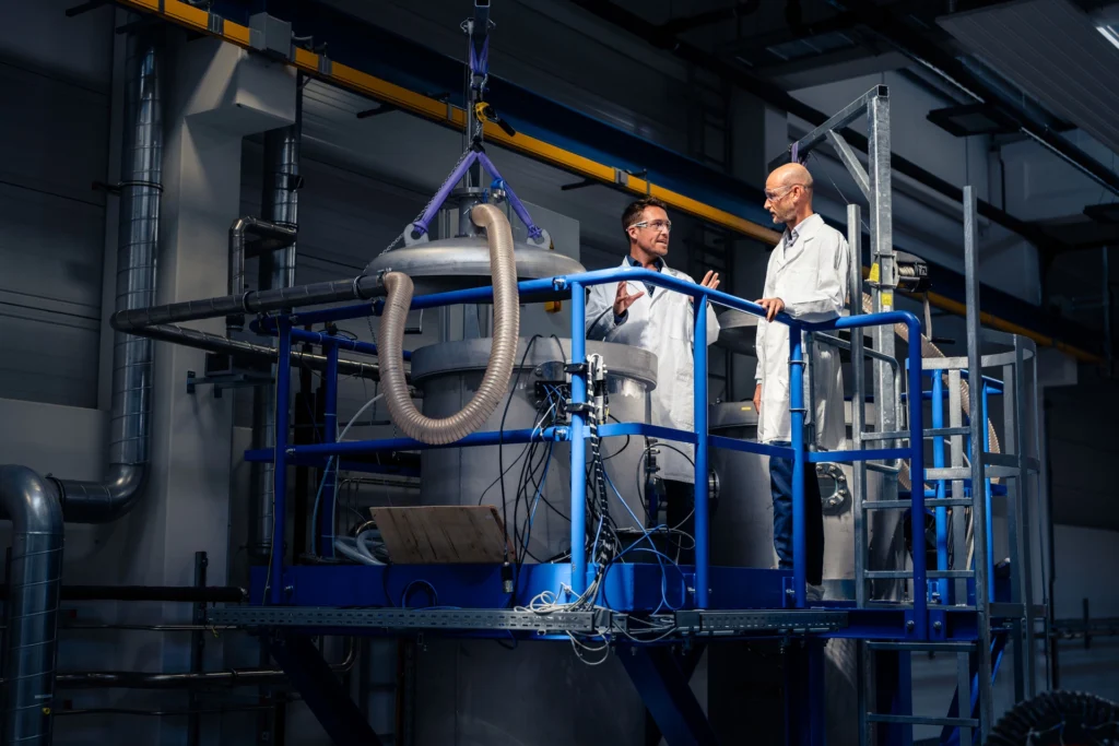 Businessfotografie: Zwei Mitarbeiter des Helmholtz-Zentrum Dresden-Rossendorf stehen an einer ihrer Forschungsaparaturen und besprechen ein Projekt